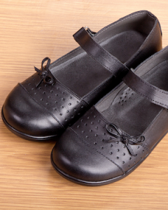 a pair of black 'mary-Jane' shoes on a wooden floor